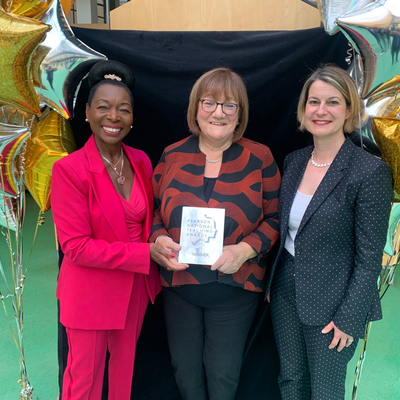 One person holding an award that reads “Pearson National Teaching Awards - Winner”, standing between two people.