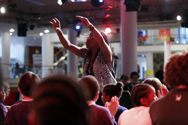 Tutor with arms raised directing a children’s choir.